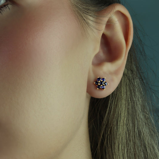 GIOVE MIO: Classic 10kt Yellow Gold Sapphire Flower Earrings - Add a touch of elegance with these blue sapphire studs! Featuring 14 round sapphires totaling 0.84 CTW and butterfly backs, stand out with style and sophistication! Make them yours today!