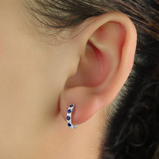 GIOVE MIO 14kt White Gold Huggies with Blue Sapphires and Diamonds. Elegant huggie earrings featuring 8 blue sapphires and 16 diamonds in a charming design. Shine stylishly!