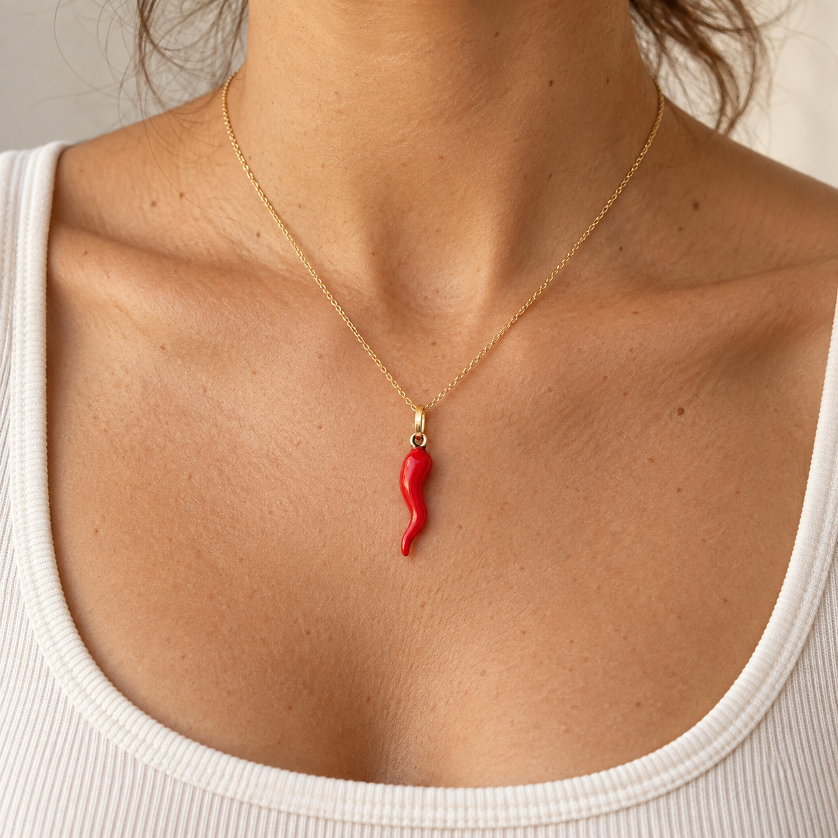 Dije cornetto de esmalte rojo en oro 18 kt sobre modelo; cadena de presentación.